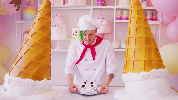 Young Man Dressed As Chef Considering Cake Standing in Bright Confectionery