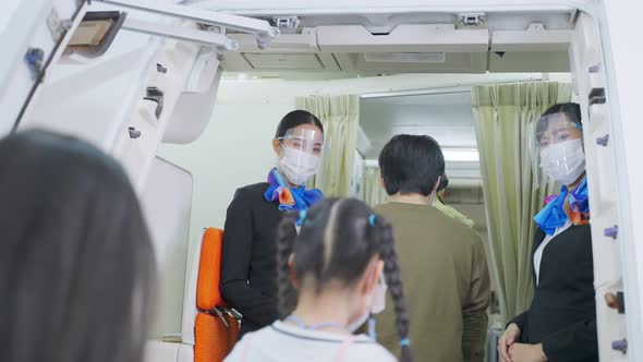 Asian beautiful flight attendants wearing face mask greeting passengers walking and coming on board.