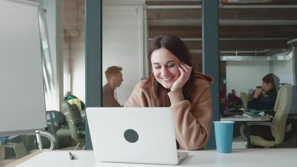 Happy Young Woman Laughing at Funny Streaming Movie on Laptop or or is in Correspondence at Office