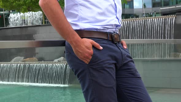 A Businessman Leans Against a Windowed Barrier, Closeup, Artificial Waterfalls in the Background