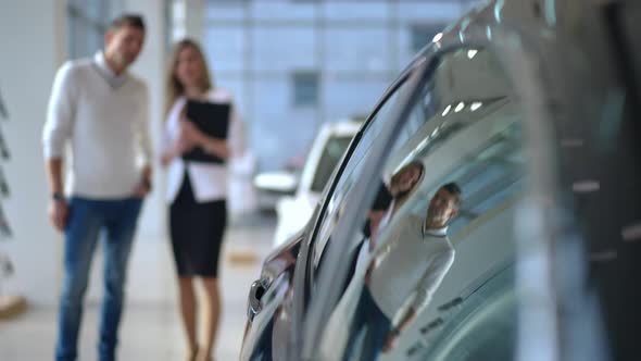 Closeup Shiny Luxurious Car Side Windows with Blurred Man and Woman Talking at Background