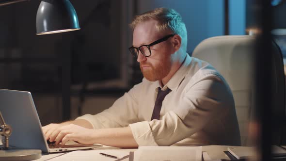 Portrait of Businessman Working on Laptop Late in Office