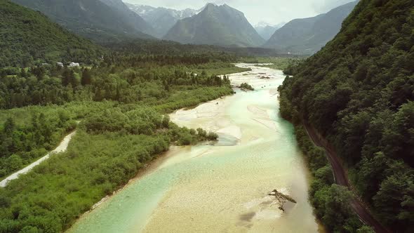 Aerial view of Soca river surrounded by many hills and vegetation in Slovenia.