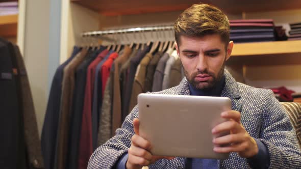 Man Working on Tablet PC at Clothing Store