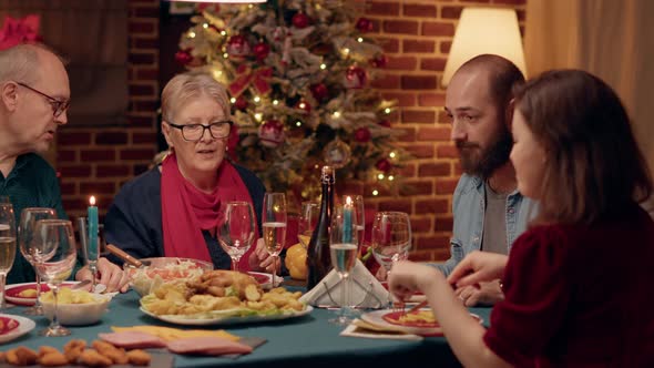 Senior Couple Talking to Married Young Adults While Enjoying Traditional Home Cooked Food at