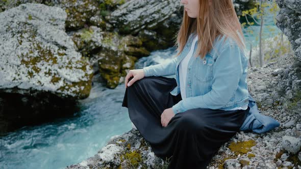 Young woman meditates near the waterfall and the river in Montenegro in the spring.