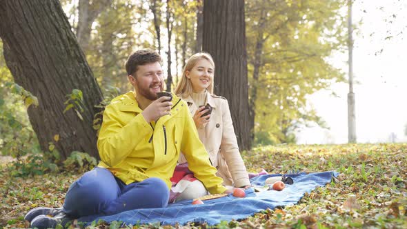 Husband and Wife Have a Picnic in Autumn Forest Near a Big Tree They Drink Coffee Tea and Enjoy