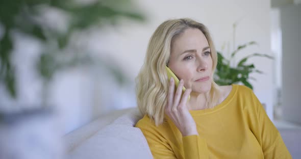 Mature woman sitting on sofa making a phone call