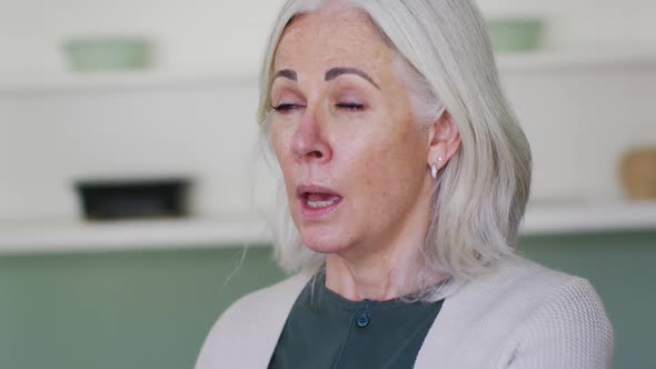 Portrait of senior caucasian woman coughing or sneezing into her arm