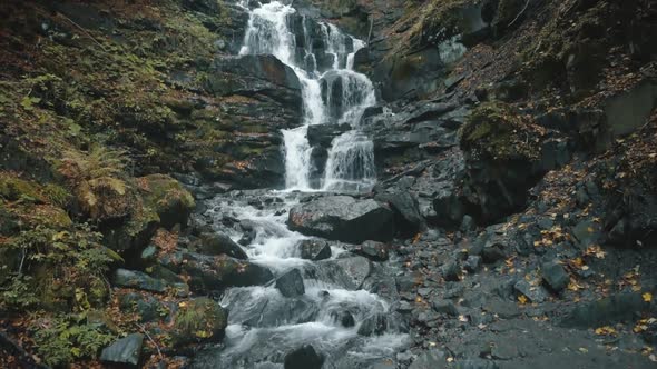 Pictorial Waterfall Flows Over Grey Large Rocks in Autumn