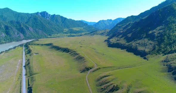 Aerial Rural Mountain Road and Meadow at Sunny Summer Morning. Asphalt Highway and River.