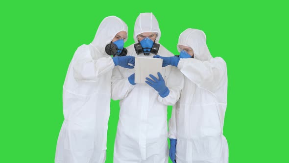 Doctors or Scientists Wearing Hazmat Suits Working Together on Digital Tablet on a Green Screen