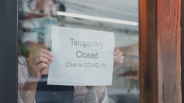 Caucasian Coffee shop owner wear mask, turns Temporary closed sign to shut down business from crisis