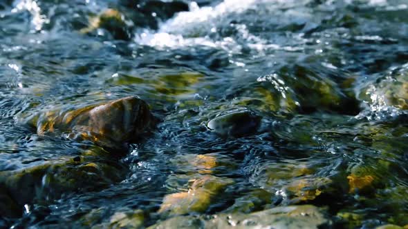 Dolly Slider Shot of the Splashing Water in a Mountain River Near Forest. Wet Rocks and Sun Rays