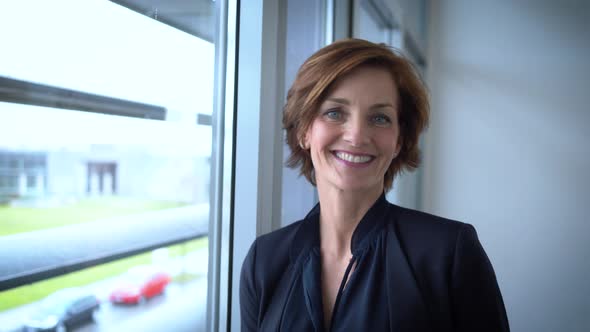 Happy businesswoman looking at smartphone at window