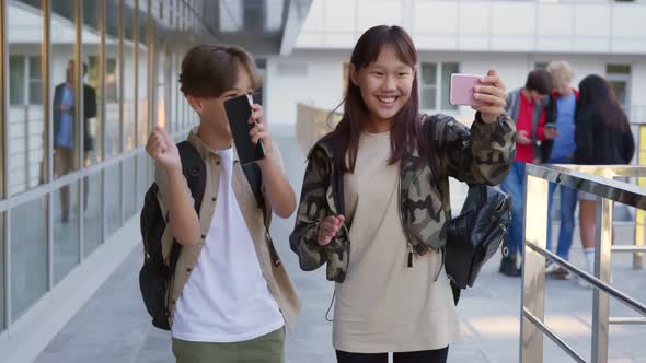 Multiethnic Teen Students Watch Funny Video on Smartphone and Dance Outdoors