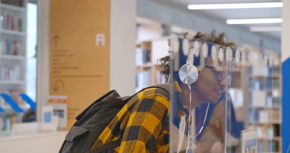 Side View of Male African Student Talking to Staff at Information Desk in College Library