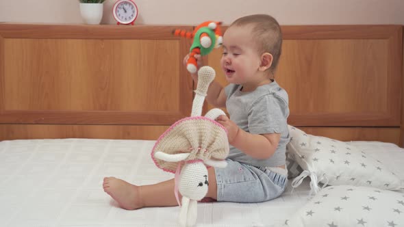 A beautiful girl of 15-20 months is playing with knitted toys tiger