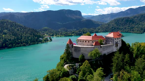 Cinematic back view of fairy tale castle surrounded by lake and mountains