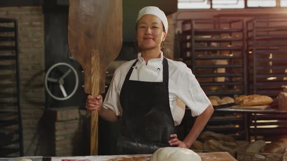 Animation of happy asian female baker holding wooden spatula