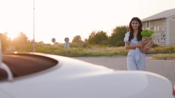 Beautiful Stylish Woman Goes to Her Luxury White Convertible with Foodstuffs