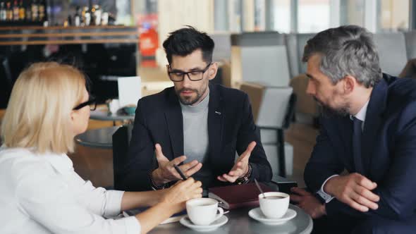 Businessman in Suit Making Business Offer To Partners During Meeting in Cafe