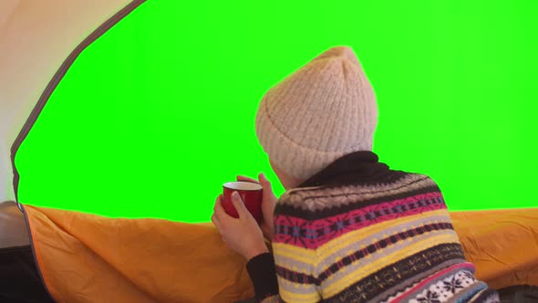 Mockup Tourism Woman Lies in a Tent with a Mug of Hot Tea and Looks at the Green Chromakey