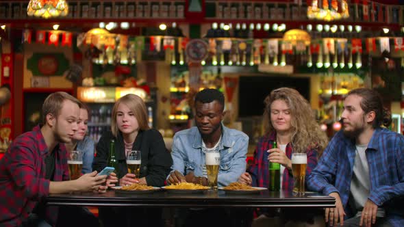 A Large Group of Friends in the Bar Sitting at the Table Laughing and Chatting Drinking Beer