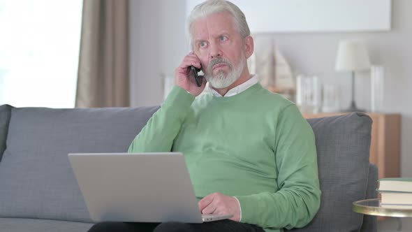 Old Man with Laptop Talking on Smartphone