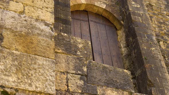 Old stone wall of ancient church with arched window 