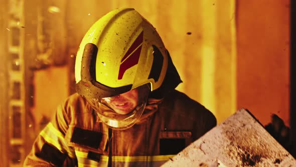 Portrait of Young Firefighter Removing Burned Wood From Burning House