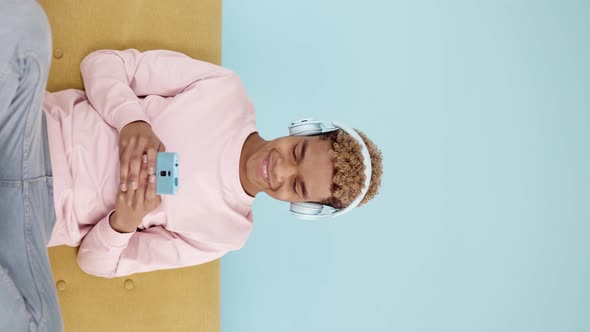 Vertical Shot of Young Hispanic Latin Man Using Mobile Phone Sitting on Sofa