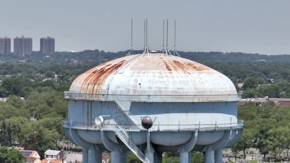 An aerial view of a light blue water tower, rusted from old age and weather. Shot on a sunny day, th