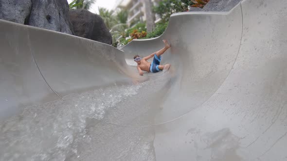 A boy plays on a waterslide water slide in a pool at a hotel resort.