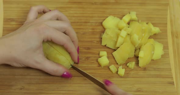 Female Housewife Hands Slicing Potatoes Into Pieces in the Kitchen