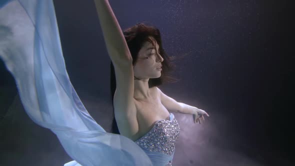 a Beautiful Girl with Long Dark Hair and a Sequined Dress Is Floating Under the Water. She Spread