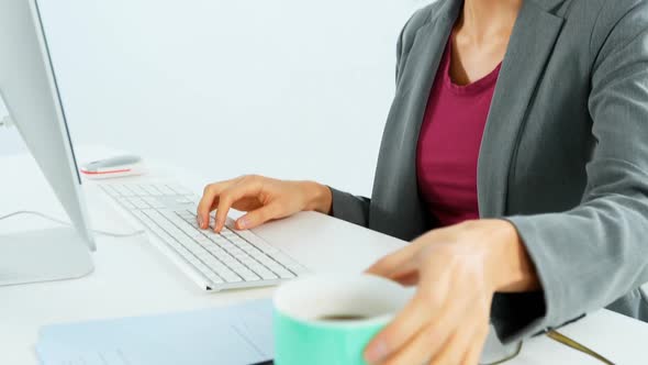 Businesswoman having coffee while working at desk