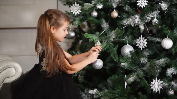 Beautiful Girl Hangs Toys on the Christmas Tree