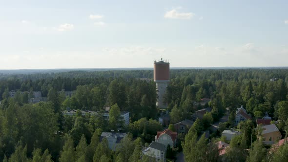 Slow aerial pan of a large watertower above the trees in Finland.