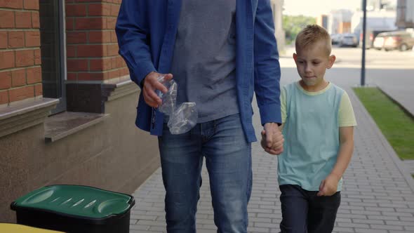 Close View of the Dad with Son Holding the Plastic Bottle and Put It Into the Special Garbage Bin