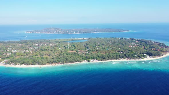 Wide drone travel shot of a sandy white paradise beach and blue water background in high resolution 