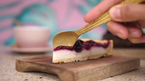 Close Up of Spoon Breaking a Piece of Raw Vegan Tofu Cake with Berries Served on a Wooden Tray