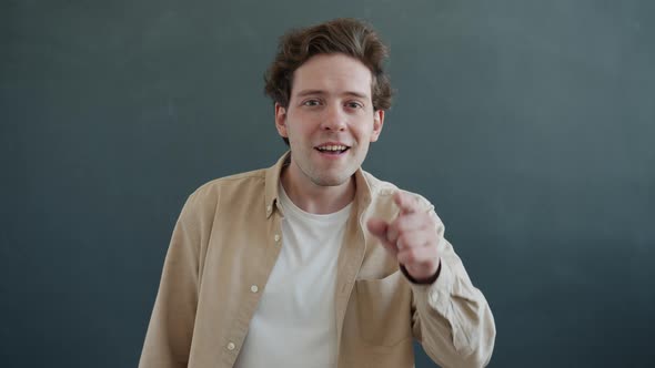 Slow Motion Portrait of Cheerful Person Pointing at Screen Smiling and Waving Hand