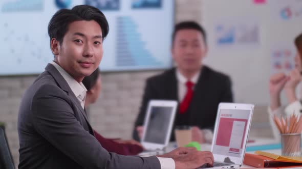 Confident young businessman sitting smiling at the camera in a meeting room