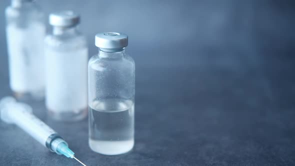 Close Up of Vaccine and Syringe on Black Background