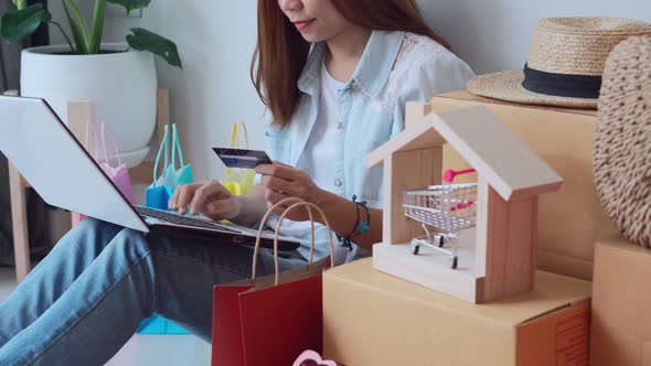 Happy young asian woman with colorful shopping bag using credit card for online shopping