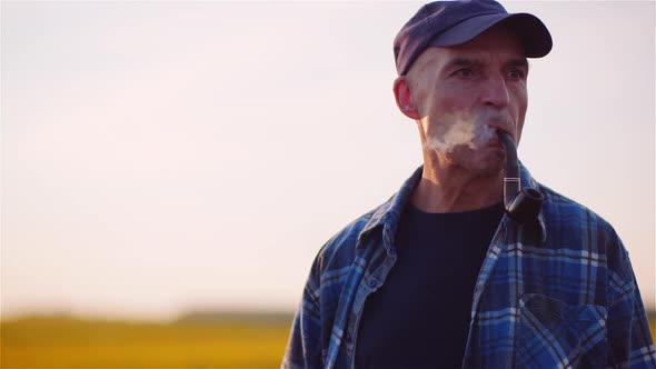 Contented Farmer Smoking His Pipe On Field Wile Examining Crops Agriculture.