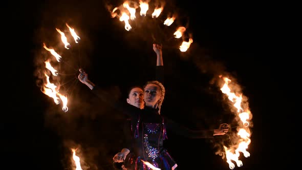 Two Girls with Large Fiery Fans Perform at Night