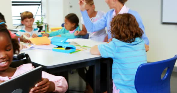 Teacher helping kids with their homework in classroom