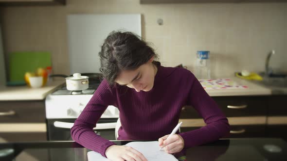 Girl student writes in a notebook, left-handed, learning at home